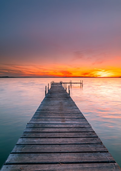 日落时海上的褐色木质船坞